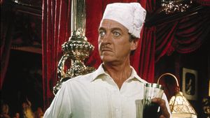 An indignant-looking man, in pyjamas and a nightcap, stands in an expensive-looking room.